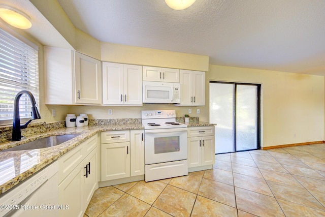 kitchen featuring light stone countertops, a sink, light tile patterned floors, white appliances, and white cabinetry