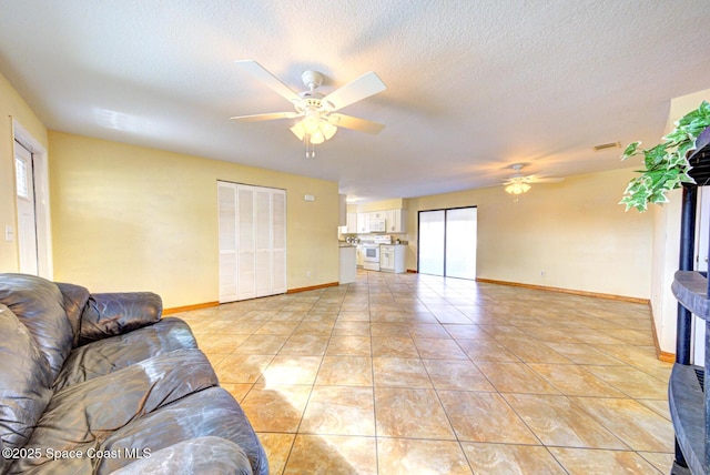 living area with visible vents, a ceiling fan, baseboards, and a textured ceiling