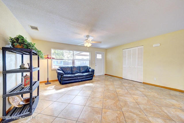 living area featuring visible vents, baseboards, a textured ceiling, a ceiling fan, and light tile patterned floors
