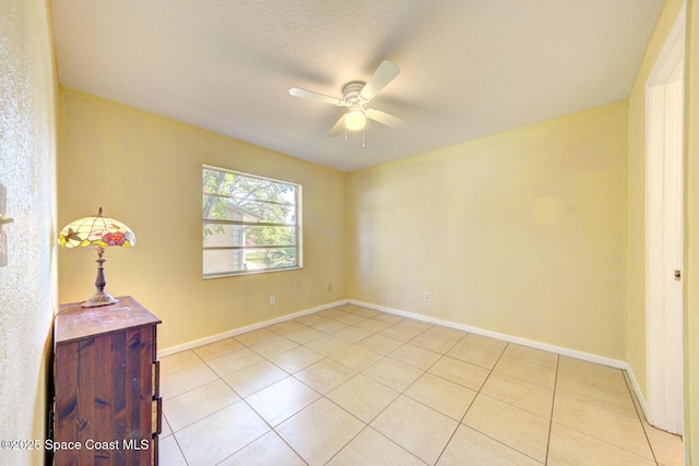 unfurnished room with a ceiling fan, baseboards, light tile patterned flooring, and a textured ceiling