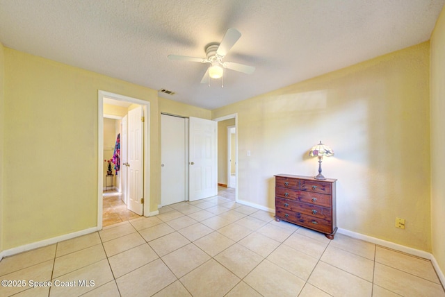 bedroom featuring visible vents, a closet, baseboards, a ceiling fan, and light tile patterned floors