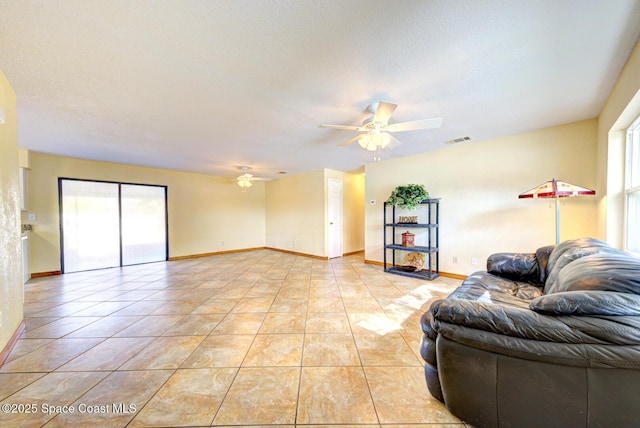 living room featuring light tile patterned flooring, ceiling fan, visible vents, and baseboards