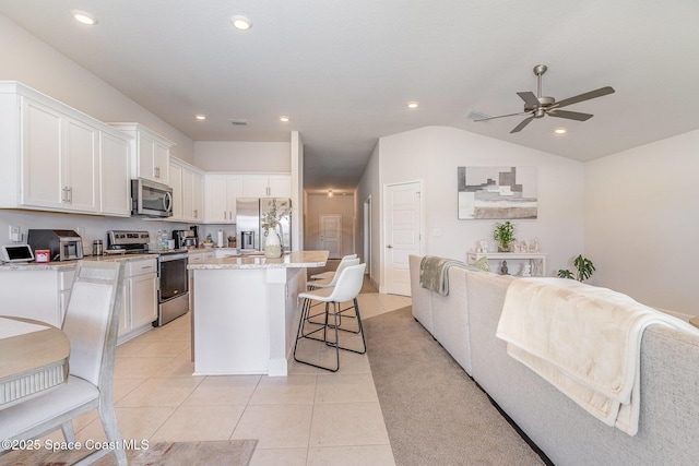 kitchen featuring open floor plan, a breakfast bar area, ceiling fan, white cabinets, and appliances with stainless steel finishes