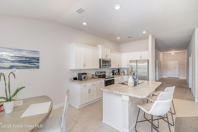 kitchen featuring a breakfast bar, a sink, stainless steel appliances, white cabinetry, and visible vents