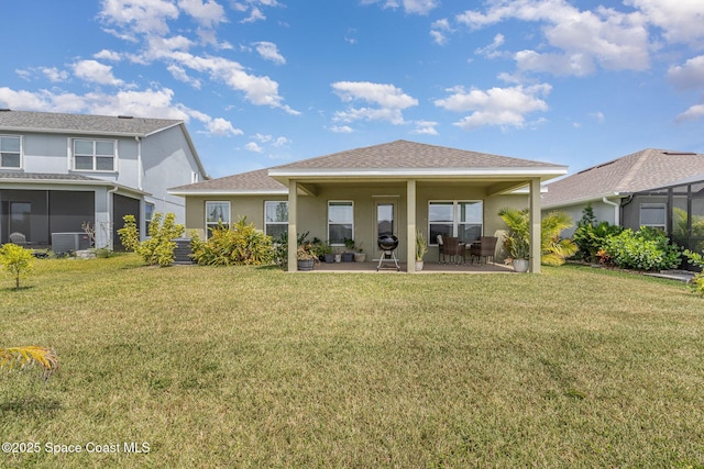 rear view of property featuring a lawn, central AC, and stucco siding