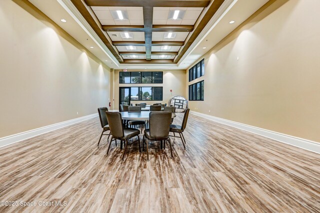 dining area with a towering ceiling, wood finished floors, and baseboards