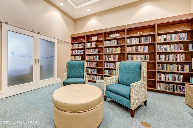 living area featuring recessed lighting, bookshelves, french doors, and carpet floors