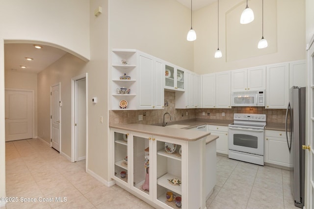 kitchen with a high ceiling, arched walkways, open shelves, and white appliances