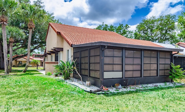 836 Brow Ct NE, Palm Bay, FL 32905 - rear view of property with a sunroom, a yard, stucco siding, and a tiled roof