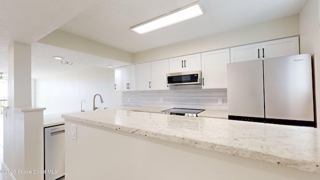 300 Columbia Dr Unit 203-2, Cape Canaveral, FL 32920 - kitchen with stainless steel appliances, tasteful backsplash, white cabinetry, light stone countertops, and a peninsula