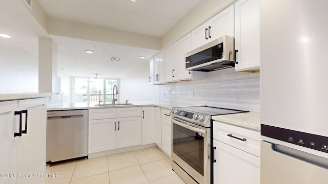 300 Columbia Dr Unit 203-2, Cape Canaveral, FL 32920 - kitchen with appliances with stainless steel finishes, a sink, decorative backsplash, white cabinetry, and light tile patterned floors