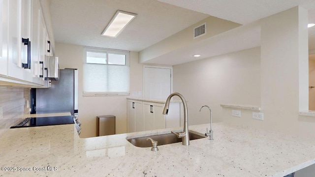 300 Columbia Dr Unit 203-2, Cape Canaveral, FL 32920 - kitchen with a sink, light stone counters, a peninsula, freestanding refrigerator, and backsplash