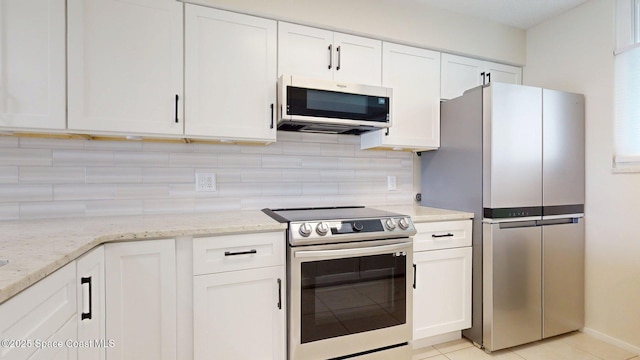 300 Columbia Dr Unit 203-2, Cape Canaveral, FL 32920 - kitchen with stainless steel appliances, white cabinets, decorative backsplash, and light stone countertops