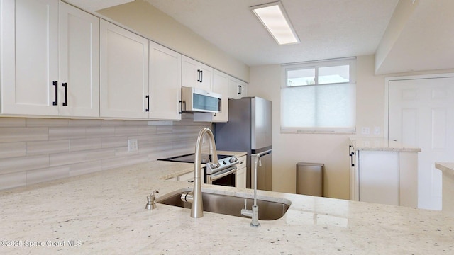300 Columbia Dr Unit 203-2, Cape Canaveral, FL 32920 - kitchen featuring stainless steel appliances, tasteful backsplash, white cabinets, and light stone countertops