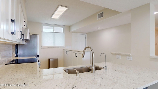 300 Columbia Dr Unit 203-2, Cape Canaveral, FL 32920 - kitchen featuring a sink, a peninsula, light stone counters, and freestanding refrigerator
