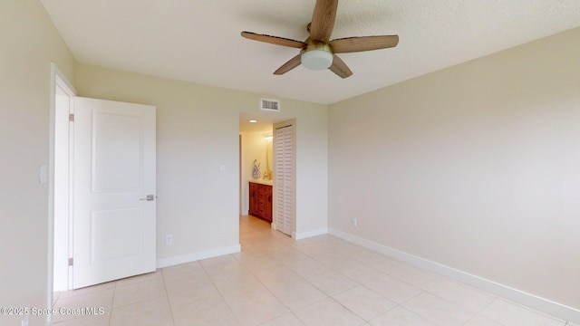 300 Columbia Dr Unit 203-2, Cape Canaveral, FL 32920 - unfurnished bedroom with baseboards, light tile patterned flooring, ensuite bathroom, and ceiling fan