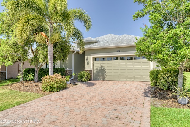 view of front of home featuring decorative driveway, an attached garage, and stucco siding