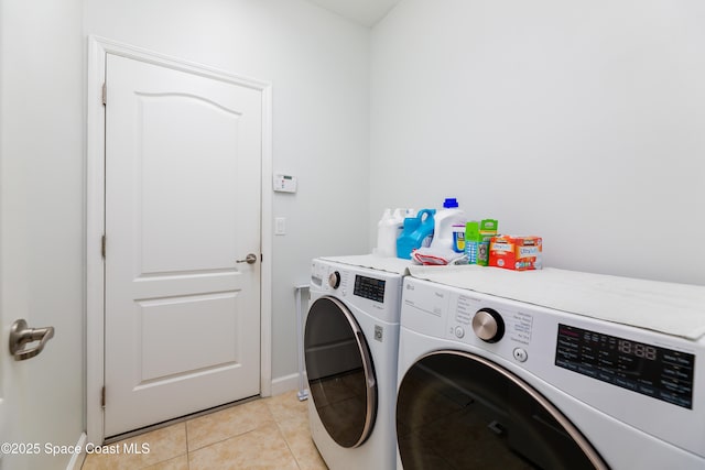 laundry area featuring laundry area, baseboards, light tile patterned flooring, and washer and dryer