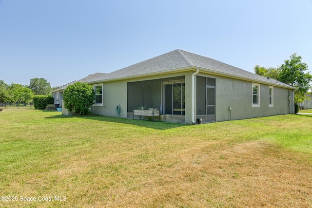 back of house with a yard, a sunroom, and stucco siding