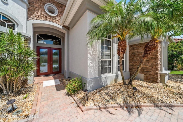 view of exterior entry with stucco siding, french doors, and stone siding