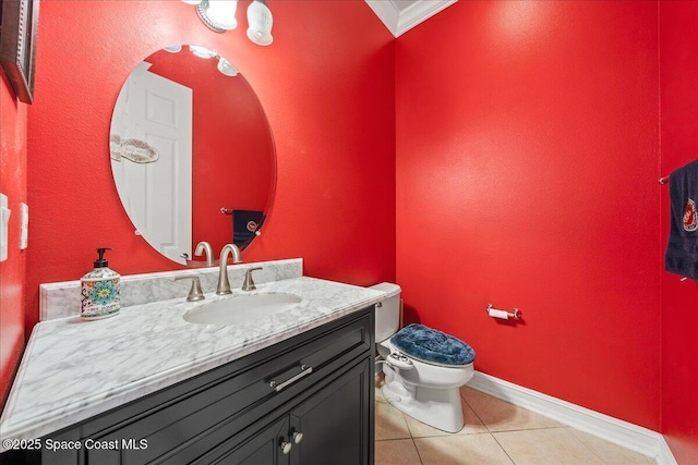 bathroom featuring vanity, ornamental molding, toilet, baseboards, and tile patterned floors
