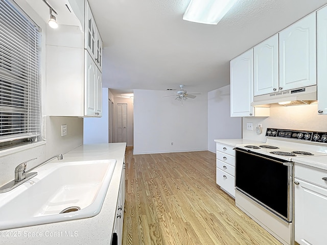537 Ebony St, Melbourne, FL 32935 - kitchen with under cabinet range hood, electric range oven, a sink, light wood-style flooring, and white cabinets