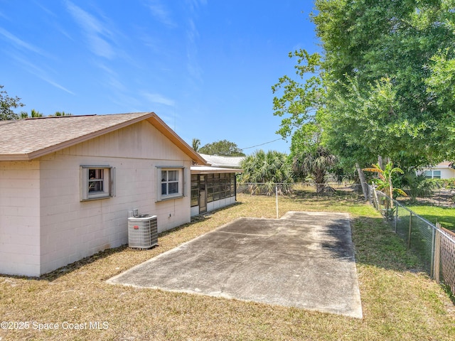 537 Ebony St, Melbourne, FL 32935 - view of side of home with central air condition unit, a sunroom, roof with shingles, concrete block siding, and a patio