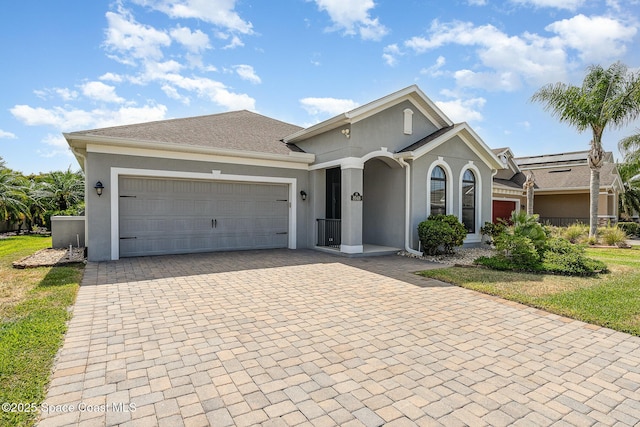 view of front facade with stucco siding, decorative driveway, and a garage
