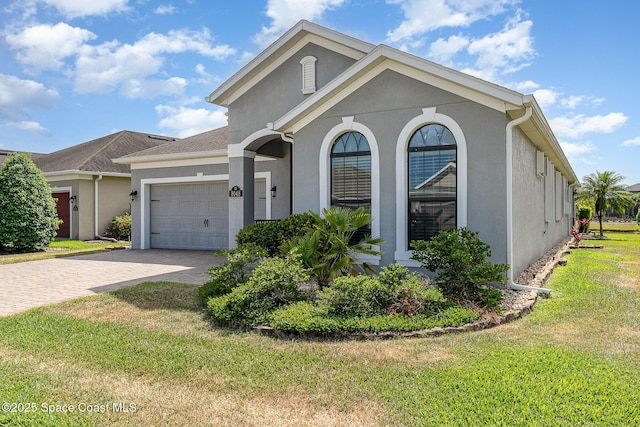 ranch-style house featuring an attached garage, decorative driveway, and stucco siding