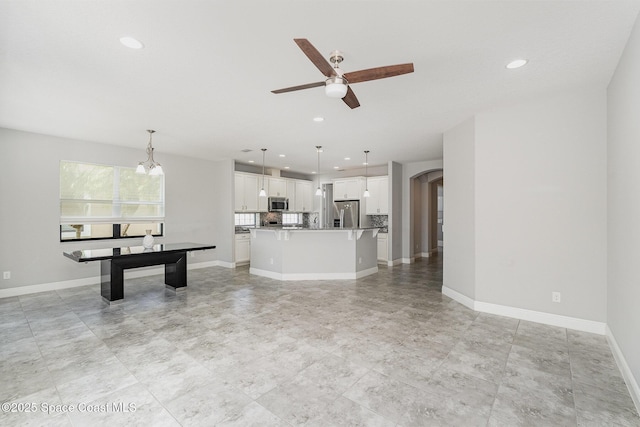 unfurnished living room with ceiling fan, recessed lighting, baseboards, and arched walkways