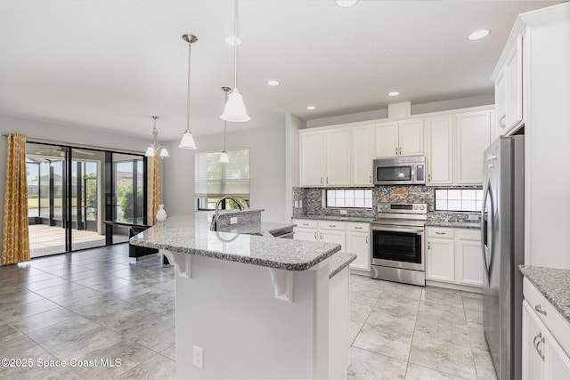 kitchen with a sink, stainless steel appliances, a breakfast bar, backsplash, and white cabinets