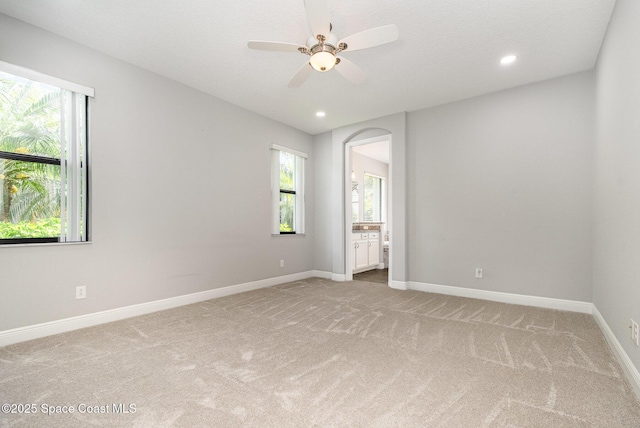 empty room featuring light colored carpet, ceiling fan, and baseboards