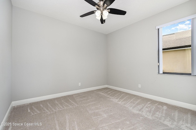 carpeted spare room featuring a ceiling fan and baseboards