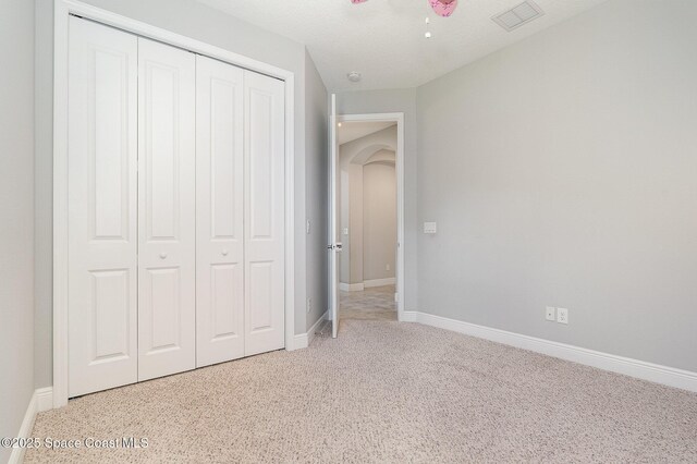 unfurnished bedroom featuring visible vents, baseboards, arched walkways, and a closet