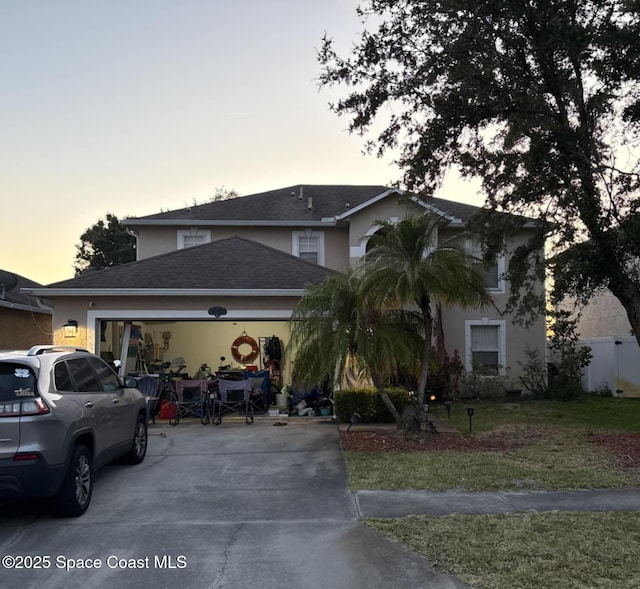 view of front of house featuring concrete driveway, a shingled roof, a front yard, an attached garage, and stucco siding