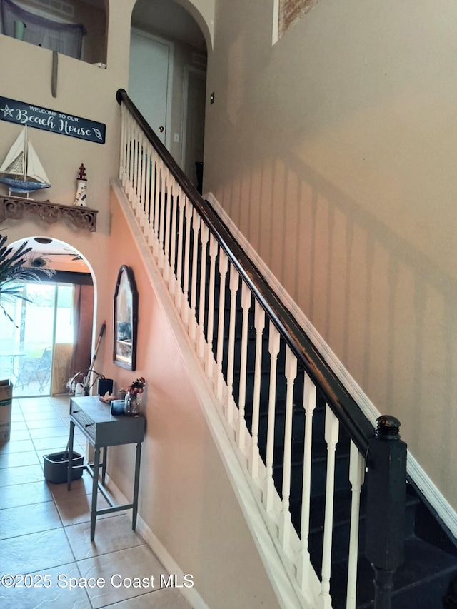 122 Morgan Cir, Sebastian, FL 32958 - staircase featuring arched walkways, baseboards, a high ceiling, and tile patterned flooring