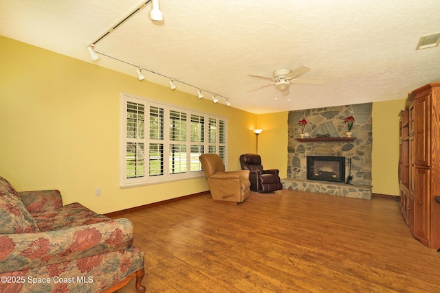 670 Kings Way, Merritt Island, FL 32953 - living room with rail lighting, a stone fireplace, wood finished floors, a ceiling fan, and baseboards