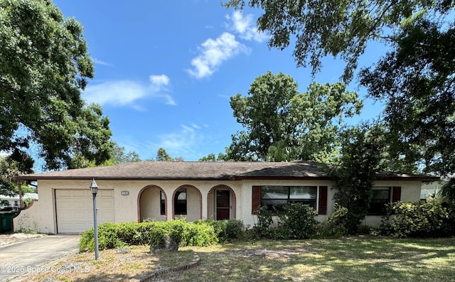 single story home featuring a front lawn, driveway, a garage, and stucco siding