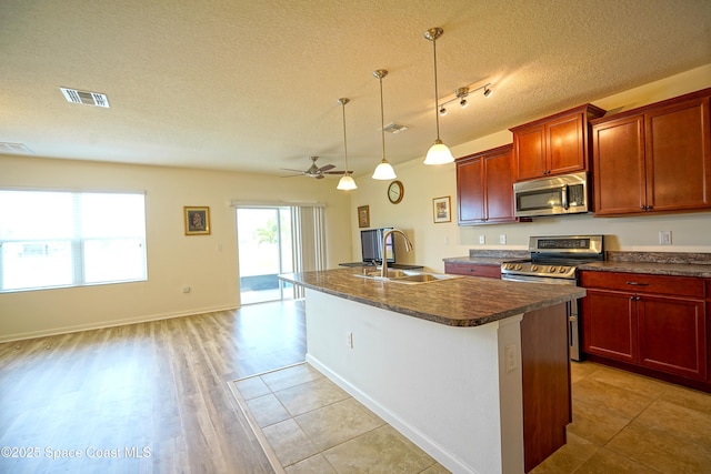 436 Great Falls Ln SW, Palm Bay, FL 32908 - kitchen with dark countertops, a sink, stainless steel appliances, visible vents, and a center island with sink