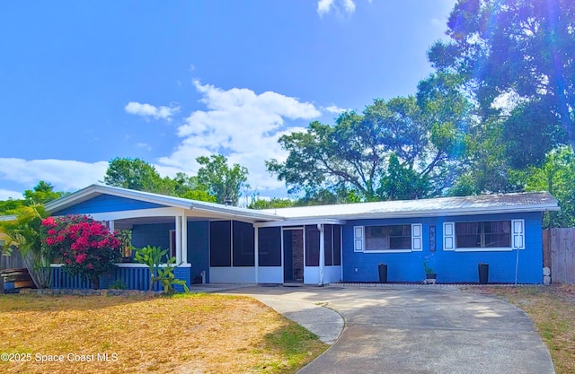 4805 Worth Ave, Titusville, FL 32780 - view of front facade with driveway, a front yard, a sunroom, fence, and concrete block siding