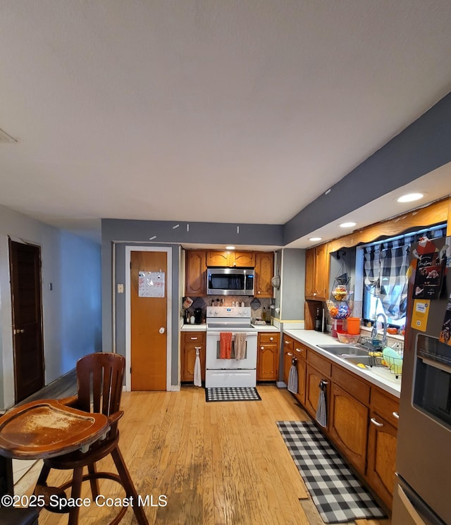 4805 Worth Ave, Titusville, FL 32780 - kitchen with brown cabinets, appliances with stainless steel finishes, a sink, light wood-style floors, and light countertops
