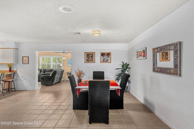 dining area featuring a textured ceiling, light tile patterned floors, and baseboards
