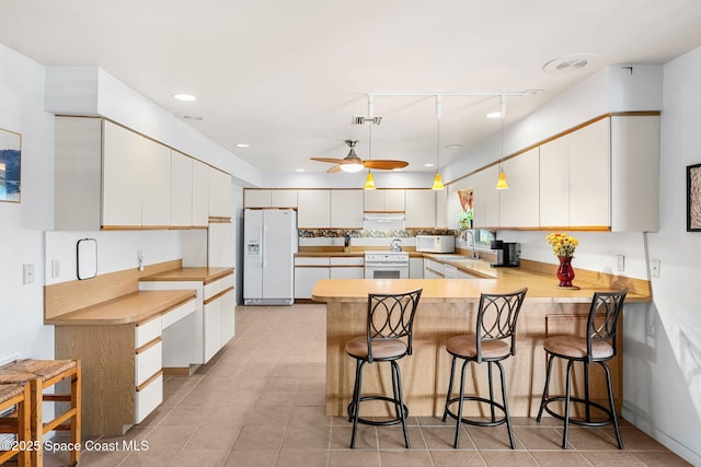kitchen with white appliances, a peninsula, ceiling fan, white cabinetry, and recessed lighting