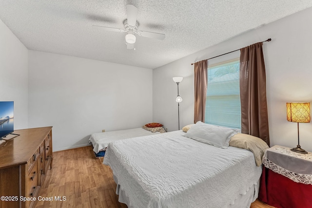 bedroom featuring light wood-style floors, a textured ceiling, and ceiling fan