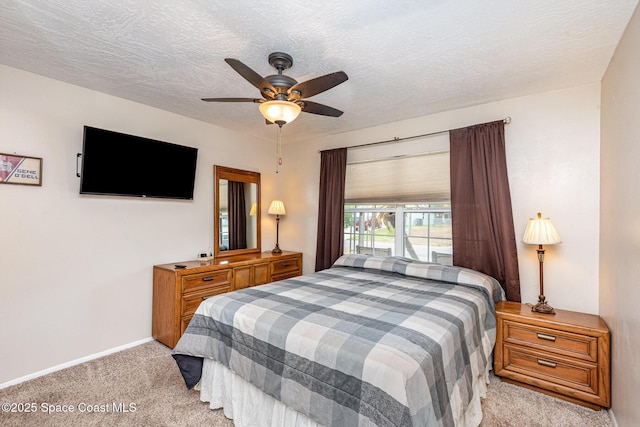 bedroom with baseboards, a ceiling fan, a textured ceiling, and light colored carpet