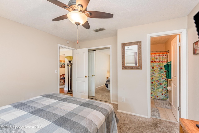 bedroom with visible vents, a closet, light carpet, a ceiling fan, and ensuite bath