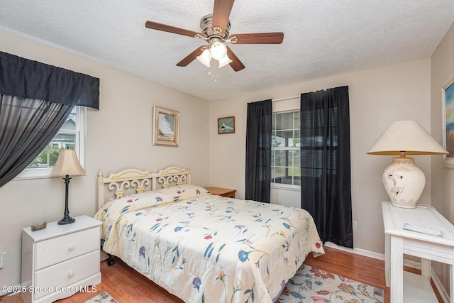bedroom featuring a textured ceiling, ceiling fan, baseboards, and wood finished floors