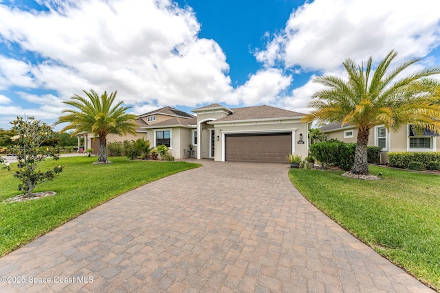 mediterranean / spanish-style home with a garage, stucco siding, a front lawn, and decorative driveway