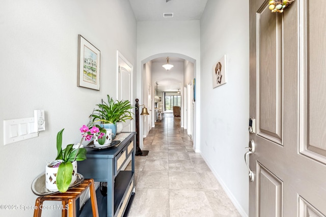 hallway with arched walkways, baseboards, and visible vents
