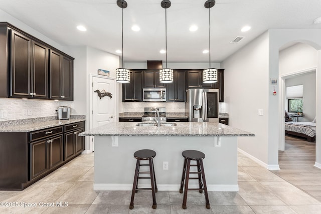 kitchen featuring backsplash, dark brown cabinetry, appliances with stainless steel finishes, and a sink